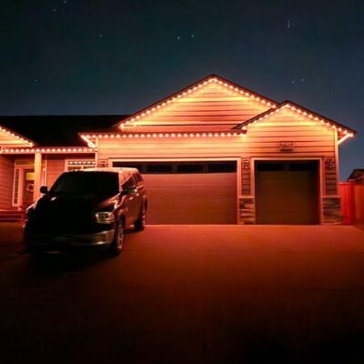 Night view of a residential house in Yelm with permanent exterior lights and a parked vehicle in the driveway.