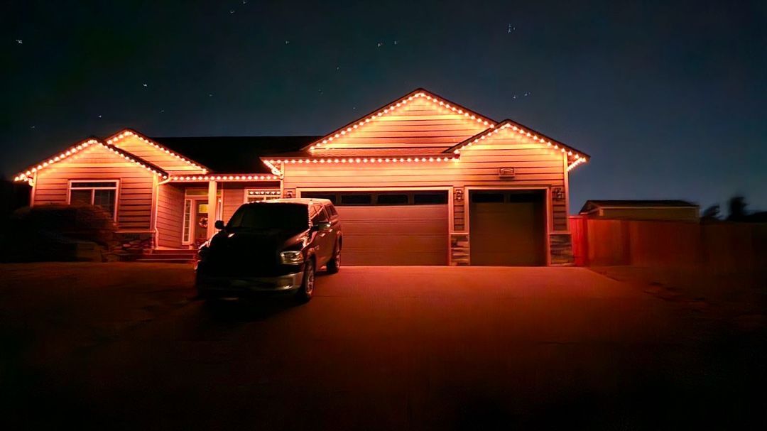 Night view of a residential house in Yelm with permanent exterior lights and a parked vehicle in the driveway.