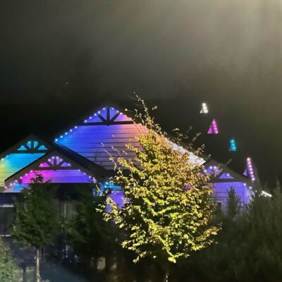 Residential home at night with colorful permanent lights on roof peaks and edges