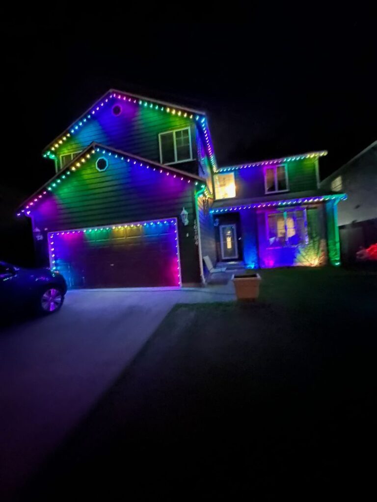 A two-story house decorated with vibrant multicolored LED lights at night.