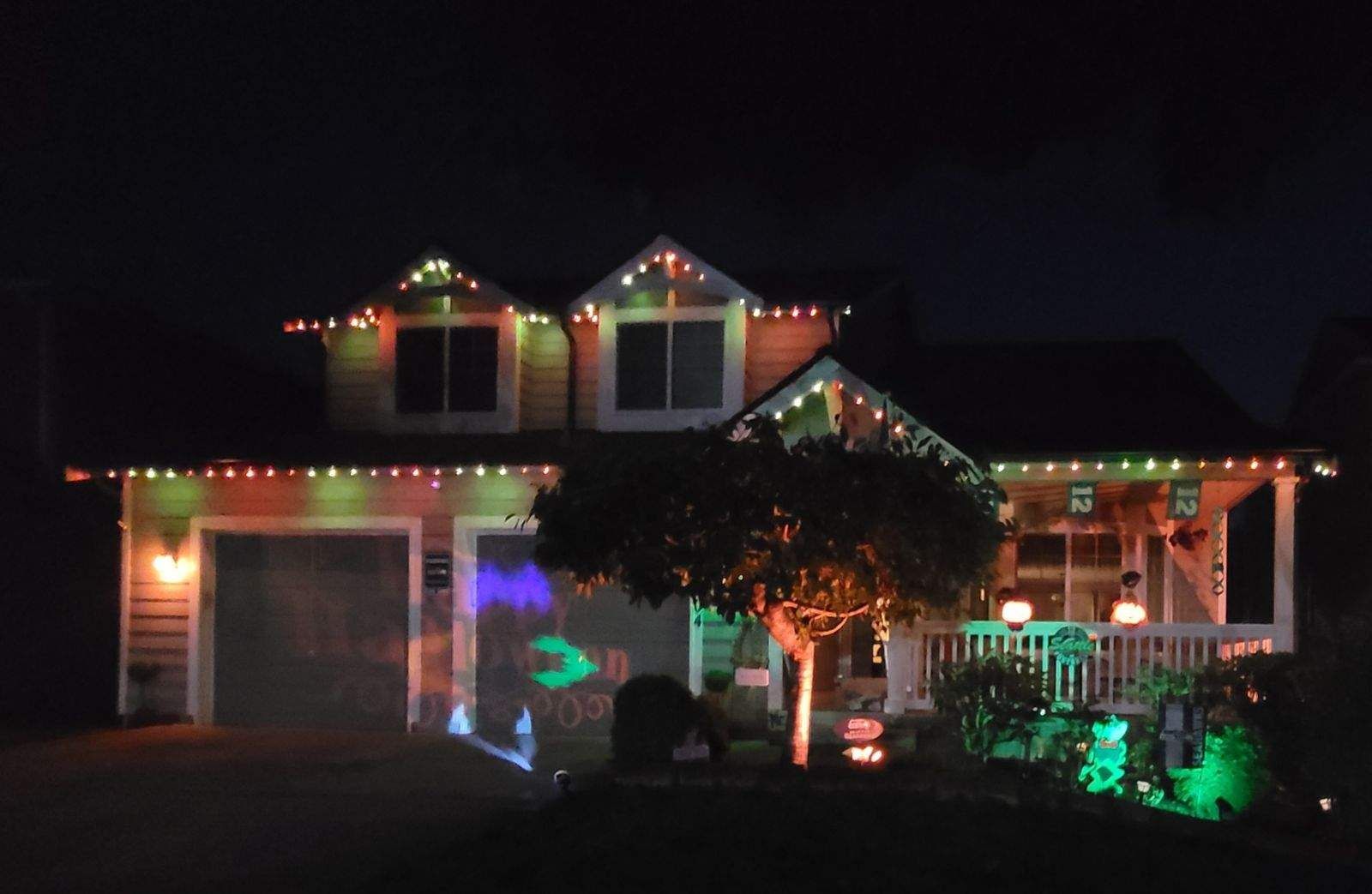 House decorated with colorful string lights and festive ornaments at night